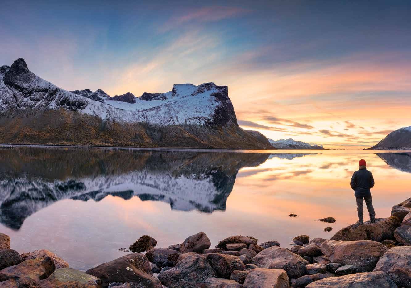 Besneeuwde Noorse bergen weerspiegeld in een stille fjord tijdens het winterlicht