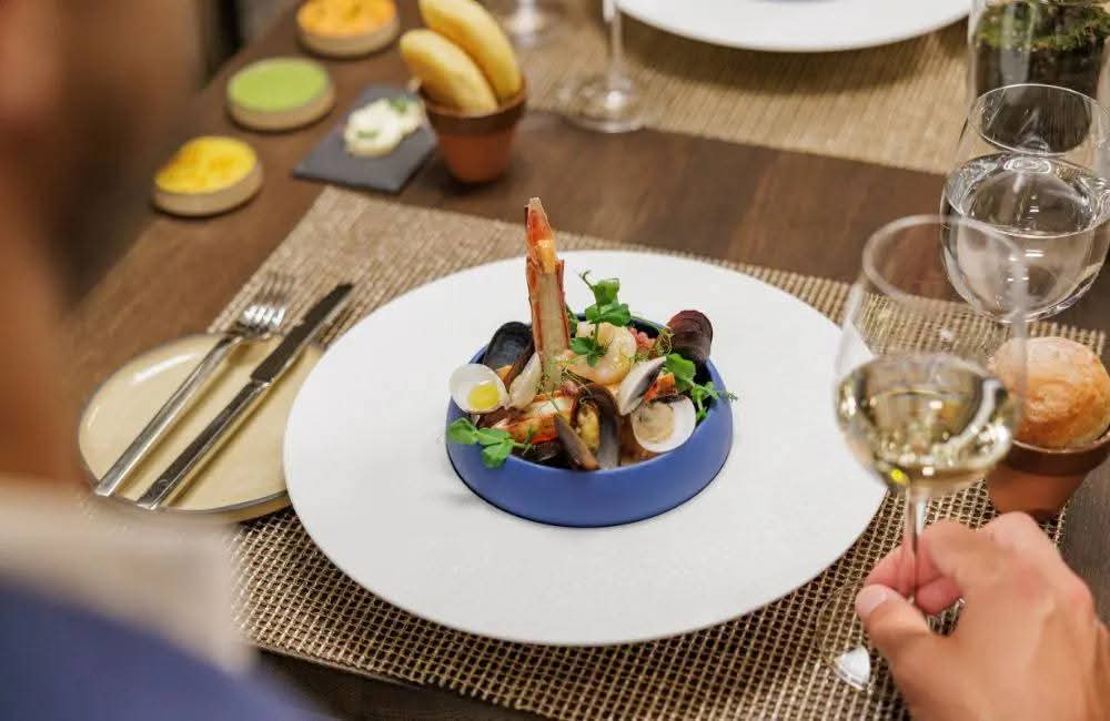 Bord met zeevruchten en een glas witte wijn aan tafel op de Silver Ray