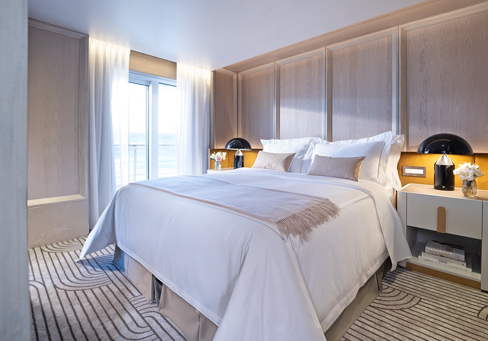 Suite met kingsize bed, lichte houten lambrisering en veranda met zeezicht